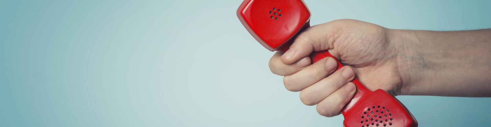 Hand greift nach roten Telefon