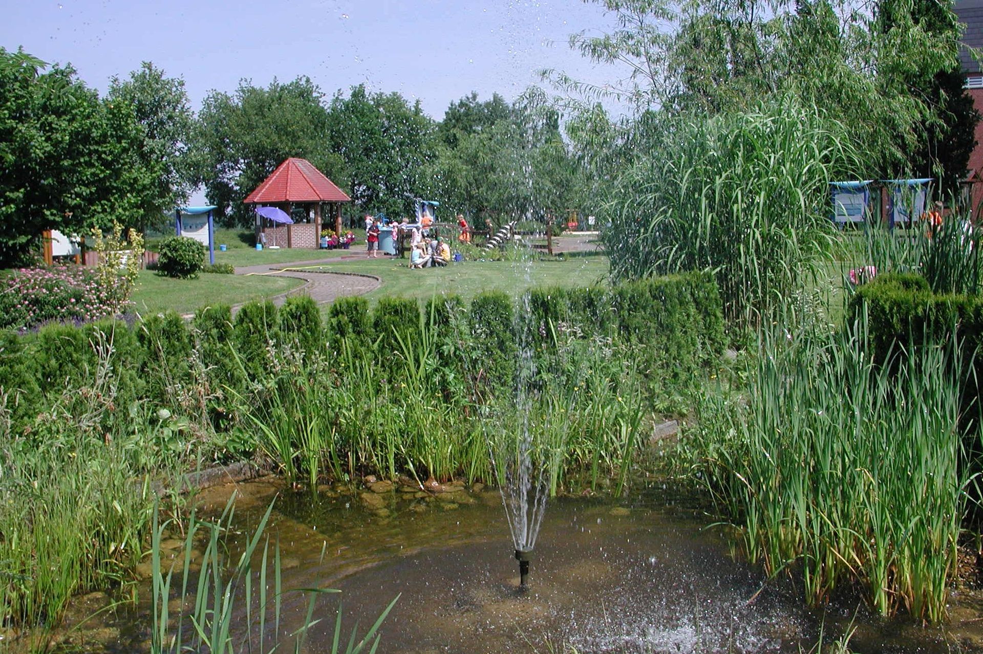 Teich und im Hintergrund eine Besuchergruppe auf dem TWE-Pfad