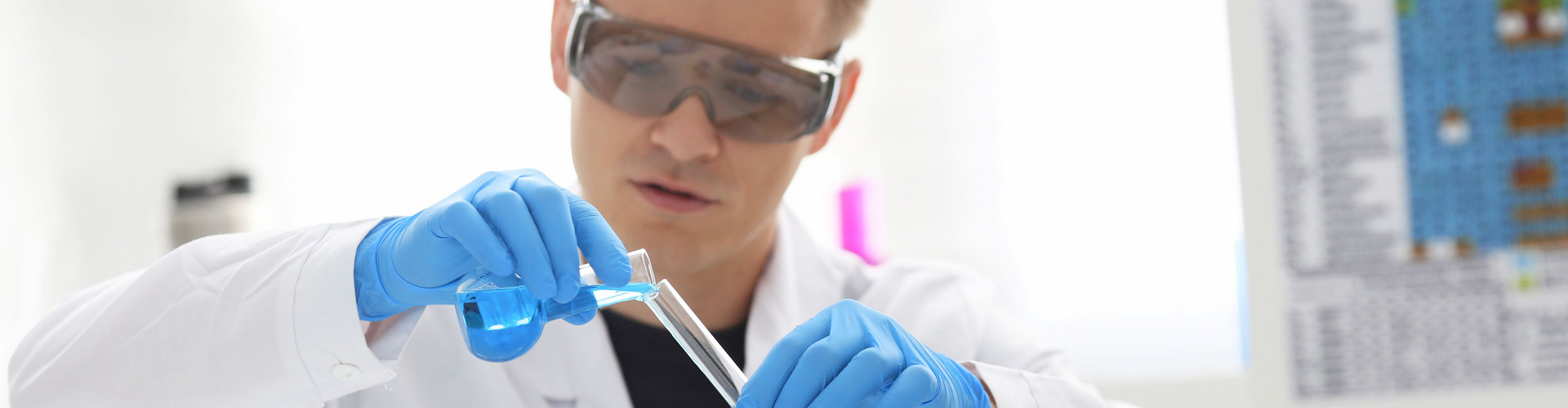 Ein männlicher Chemiker hält Reagenzglas von Glas in der Hand eine flüssige Lösung überläuft